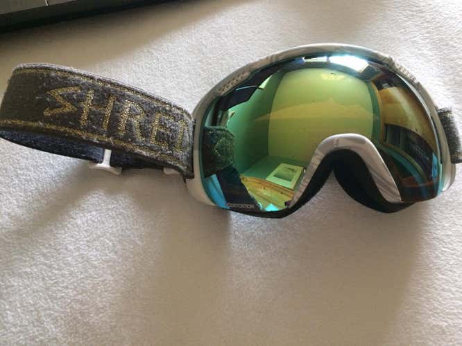 Shred goggles with gold strap and reflective lenses.