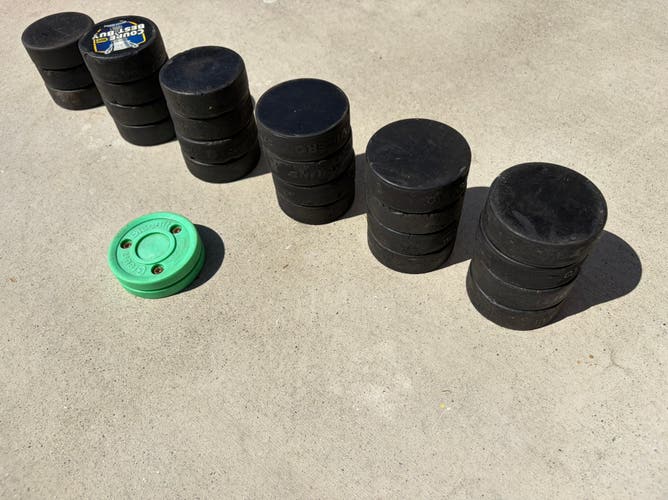 23 used but decent hockey pucks plus a green biscuit