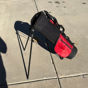 Jr Golf bag: Red Zone, lightweight black and red golf stand bag featuring built-in folding metal leg